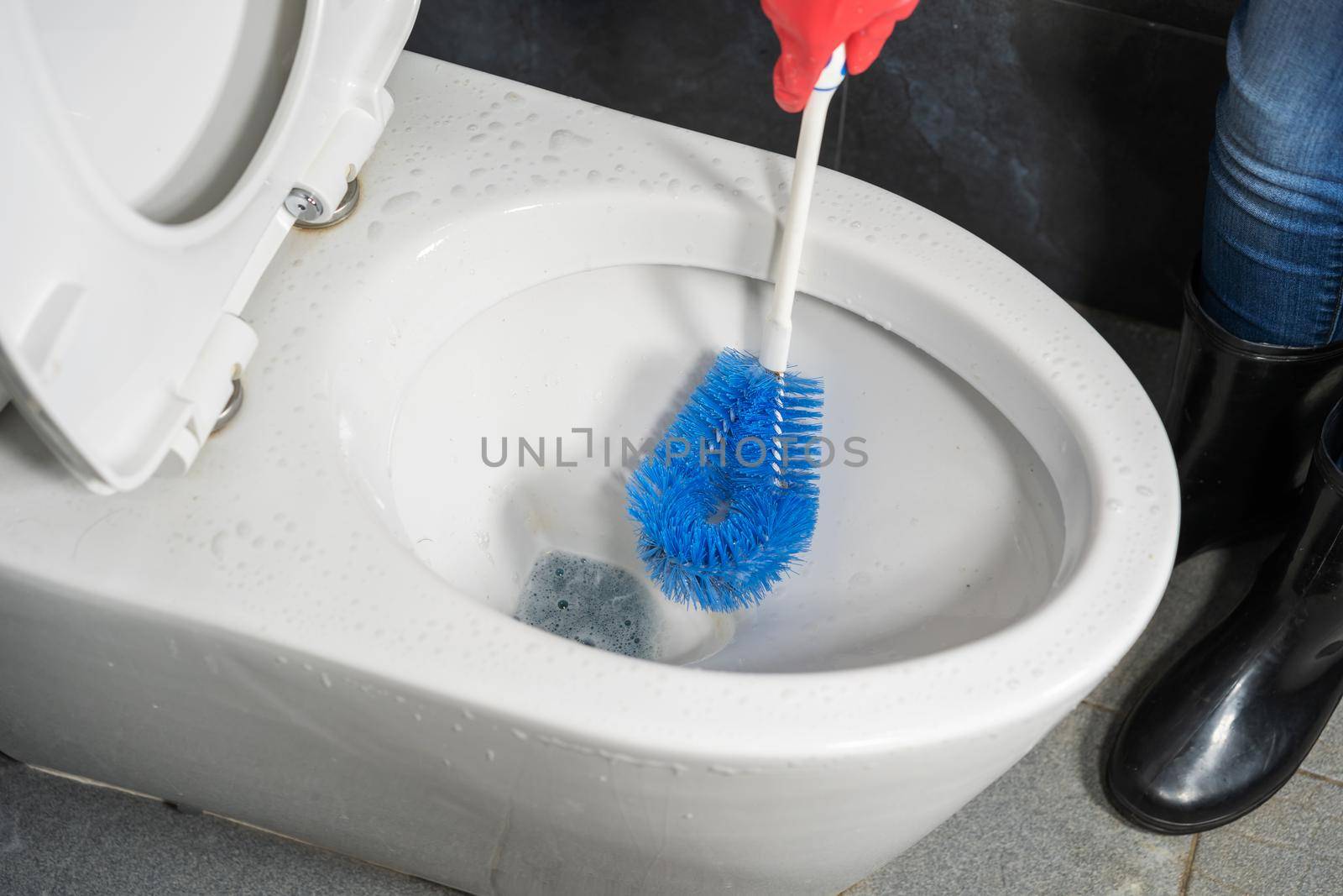 hand cleaning toilet bowl with a detergent by geargodz