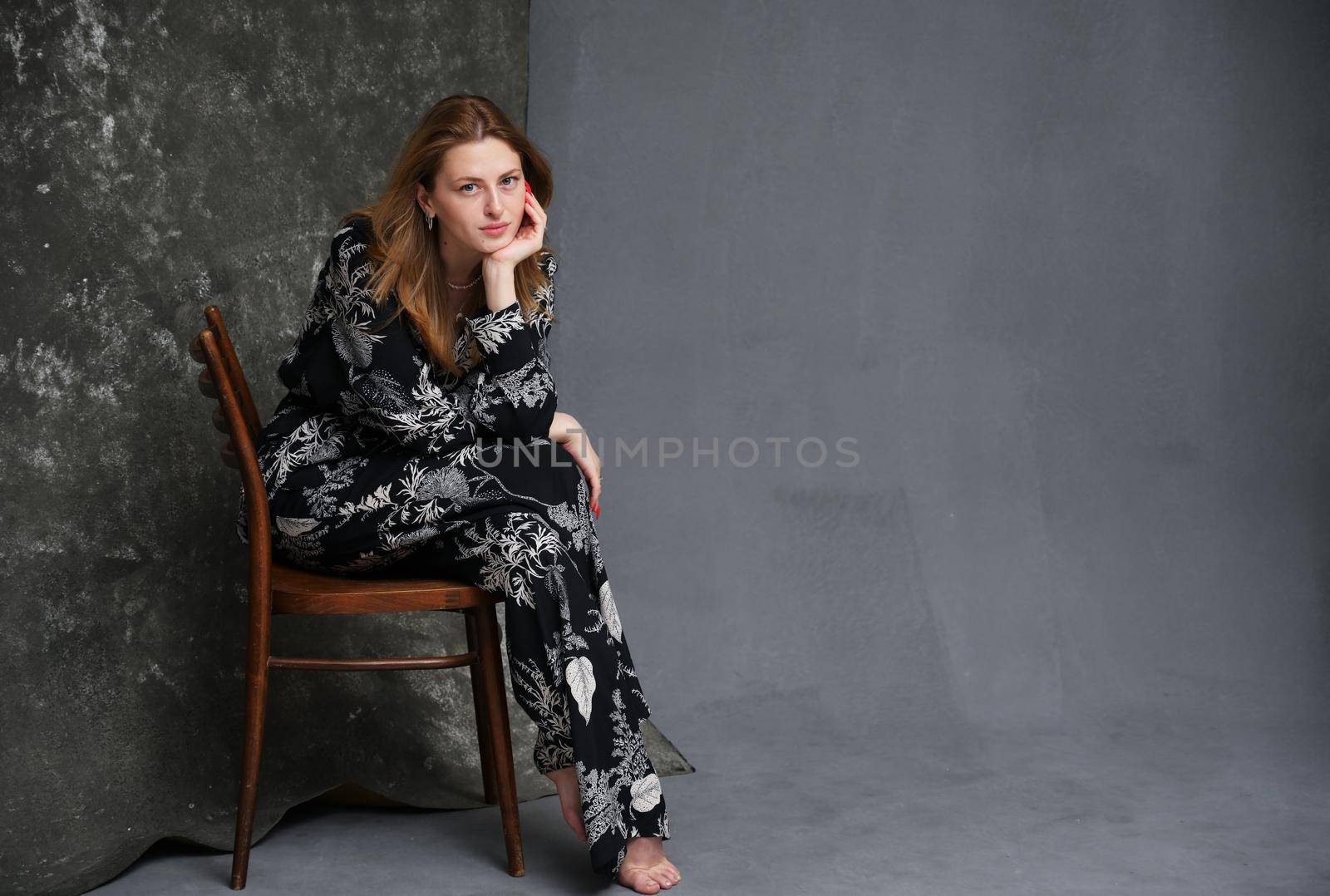 High resolution portrait of european model sitting on chair against dark background in studio