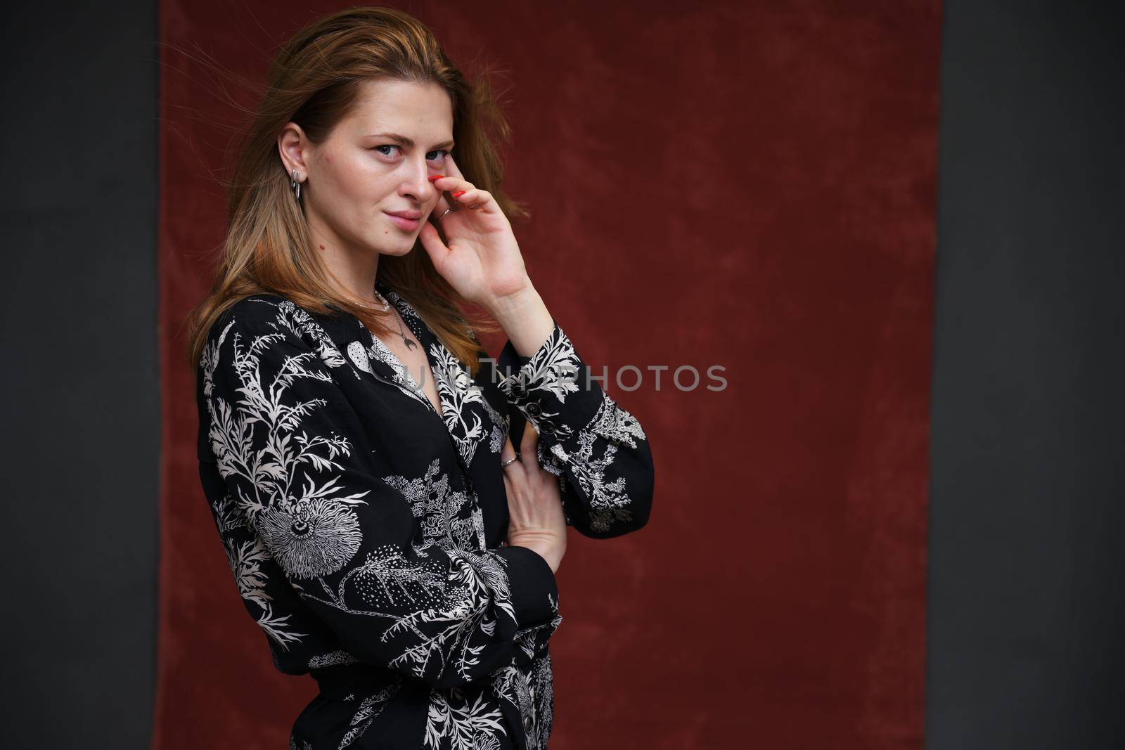 Side view of Caucasian model girl posing in studio on dark red and gray background