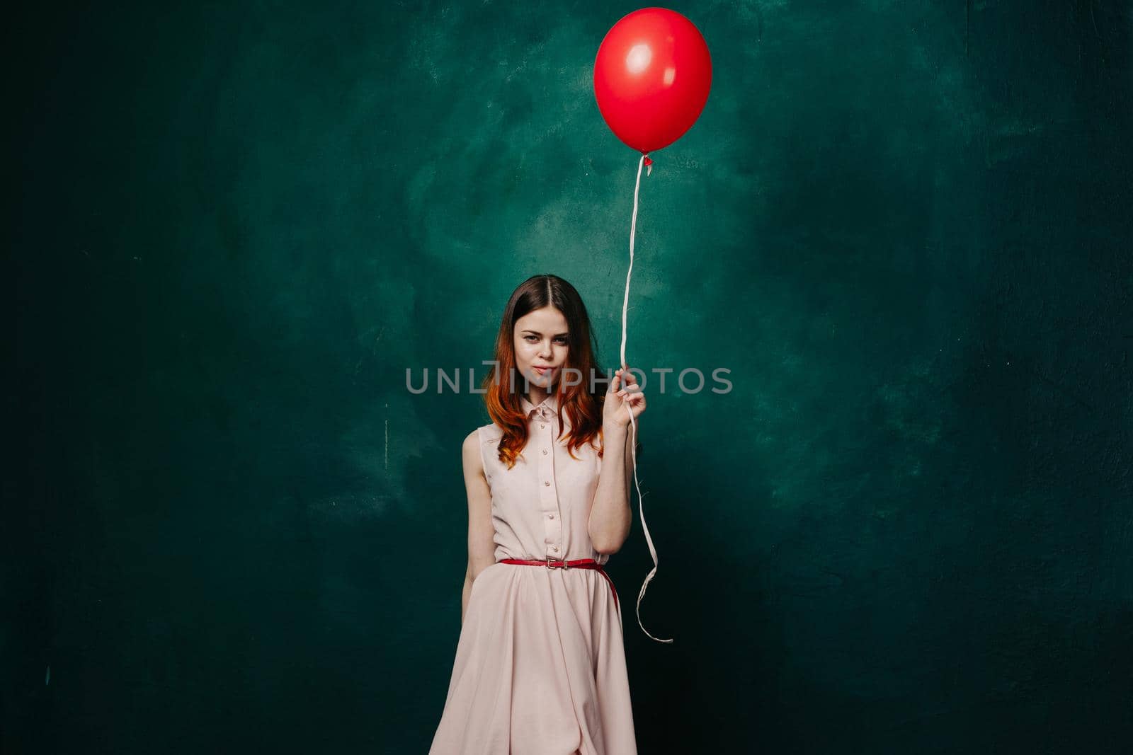 pretty woman in dress red balloon birthday green background. High quality photo