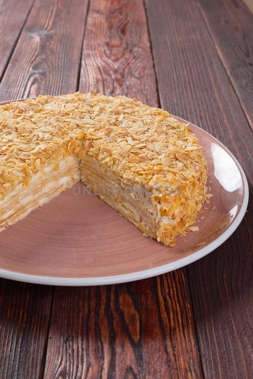 Cut caramel cake on plate on wooden table close up