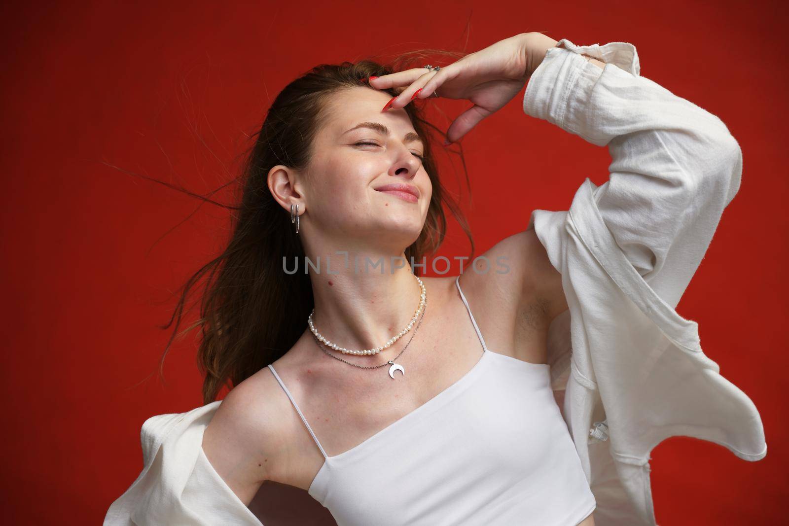 Caucasian model in white shirt shows happiness with a smile on a red background by chichaevstudio