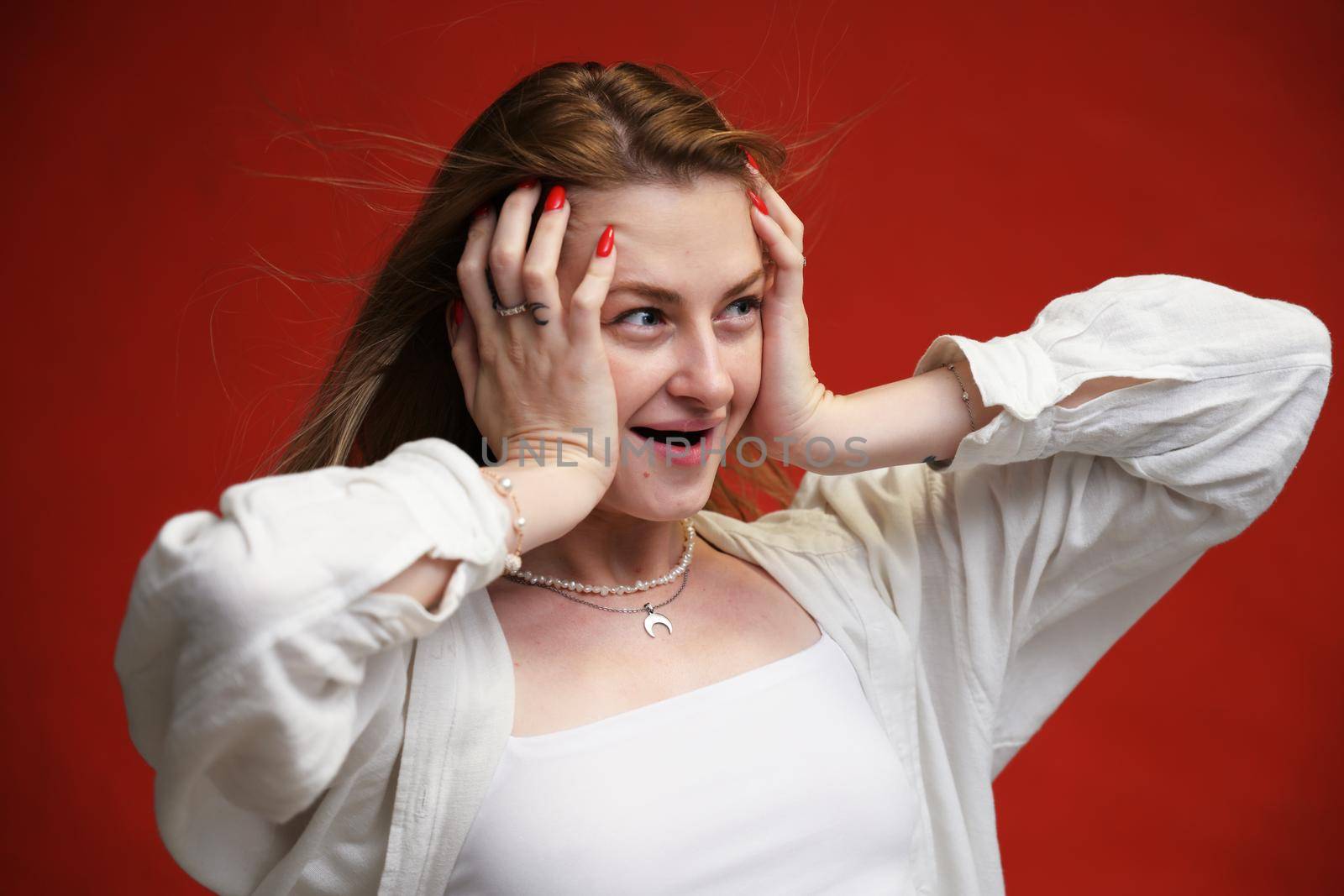 Cute caucasian girl shows surprise in the studio on a red background