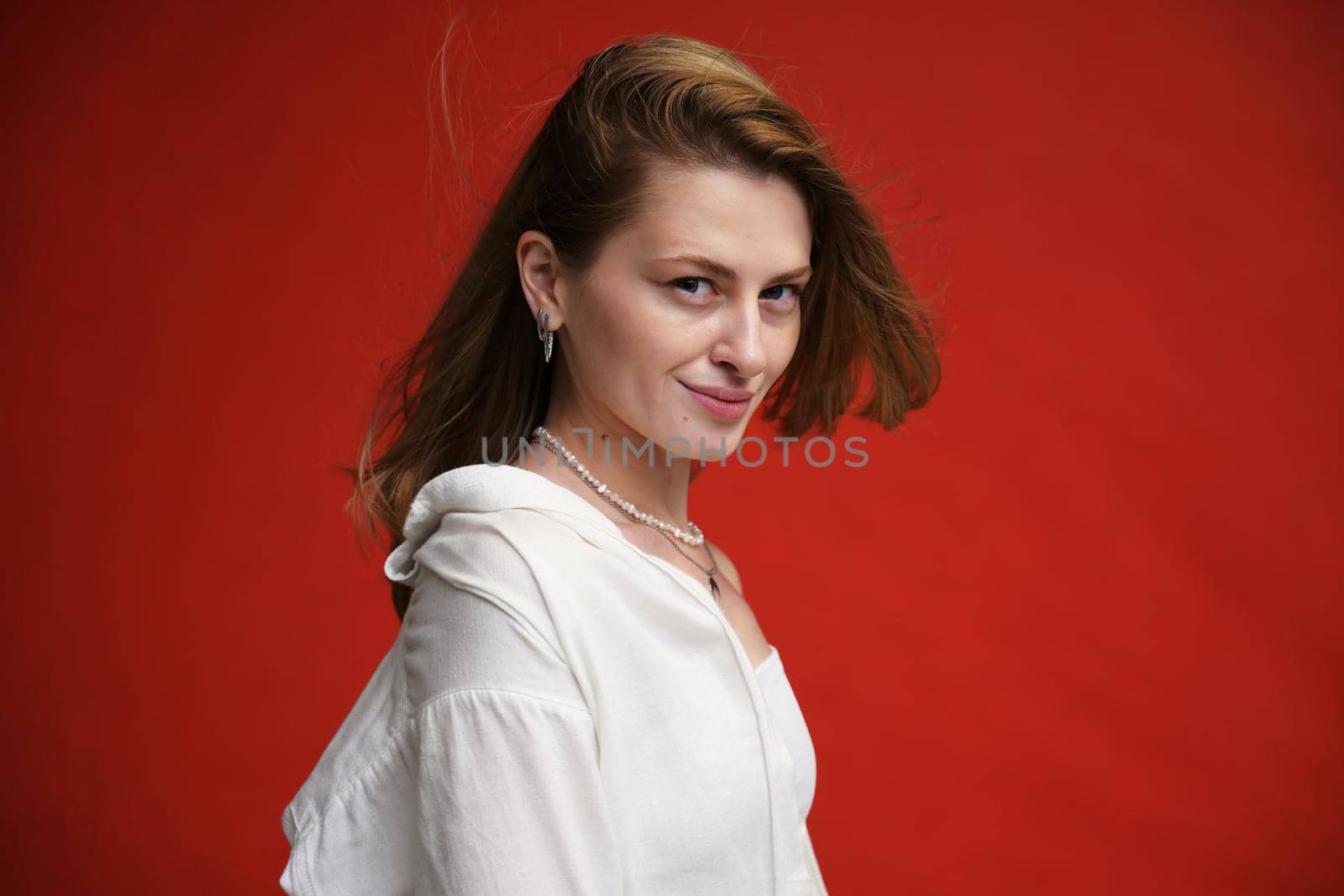 cute young caucasian girl portrait with a smile on a red background in the studio