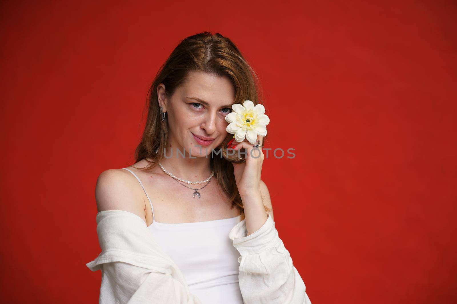 portrait with flower cute young caucasian girl with a smile on a red background in the studio by chichaevstudio