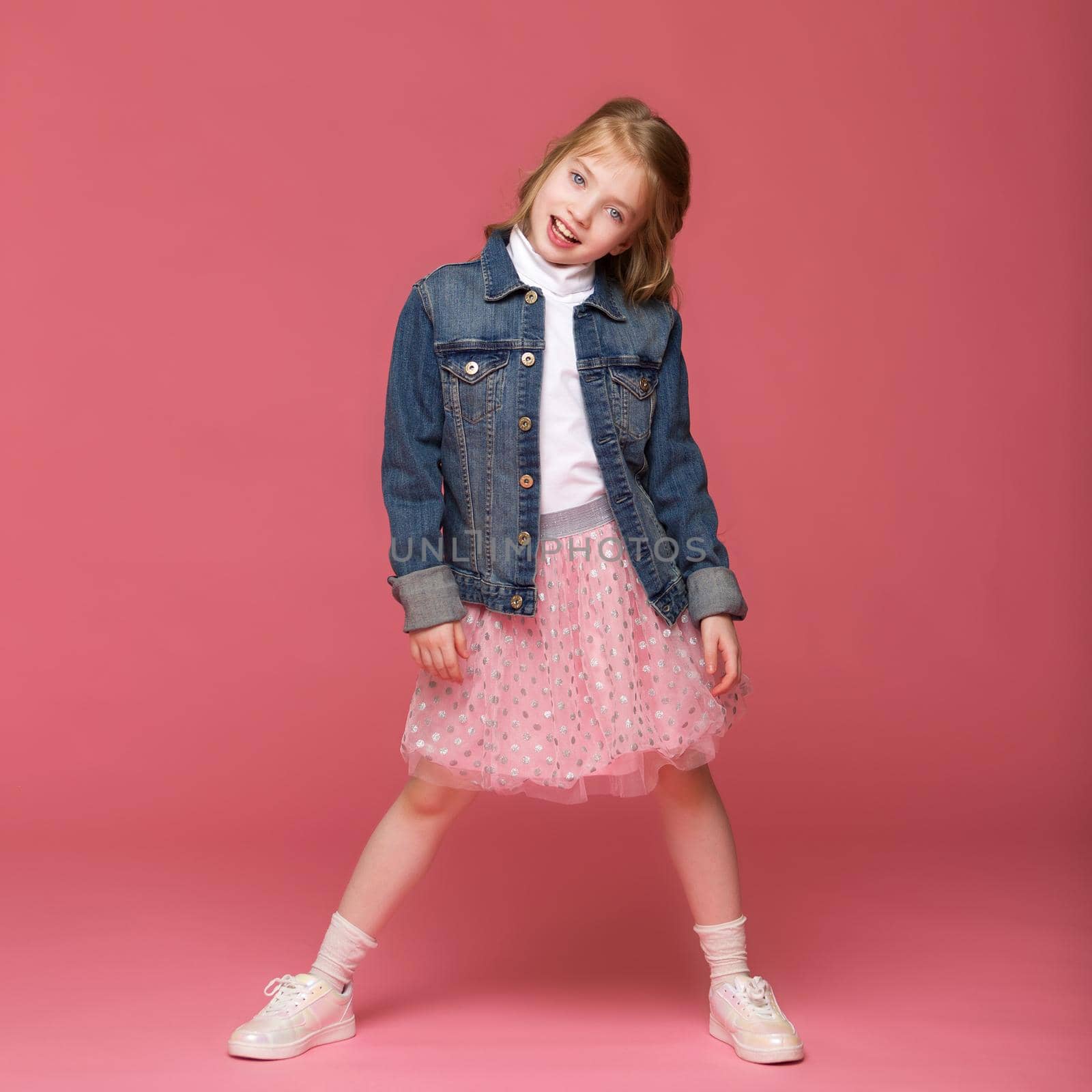 Full length shot of girl in bright dress. Adorable girl posing in studio. Shot of cute preteen child in summer silk dress and sandals looking down at camera