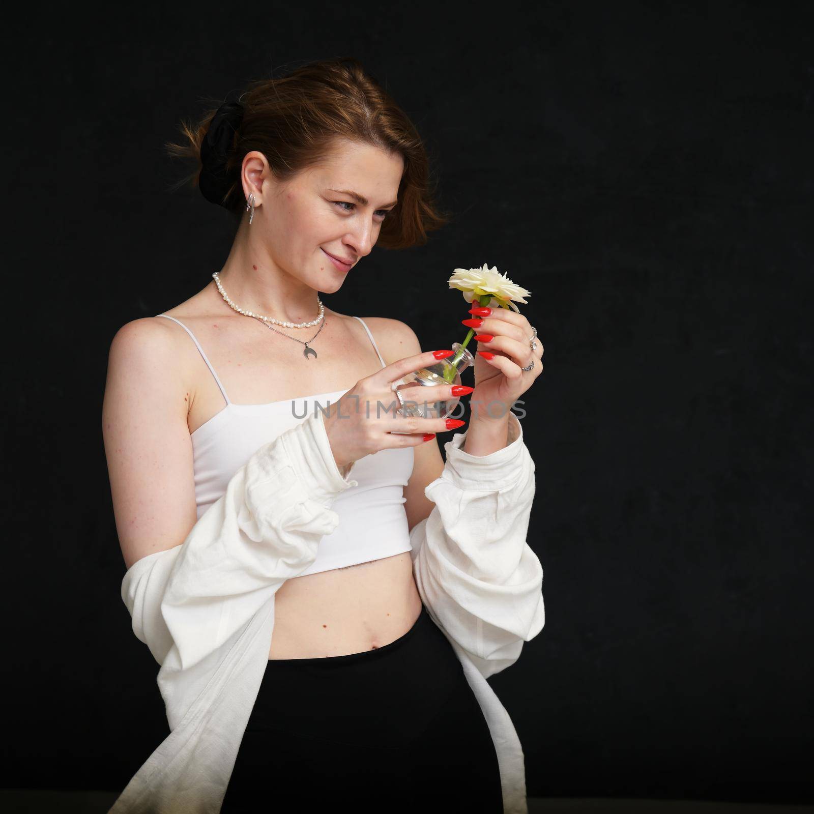 model with flower smiling girl on black background in studio in light clothes by chichaevstudio