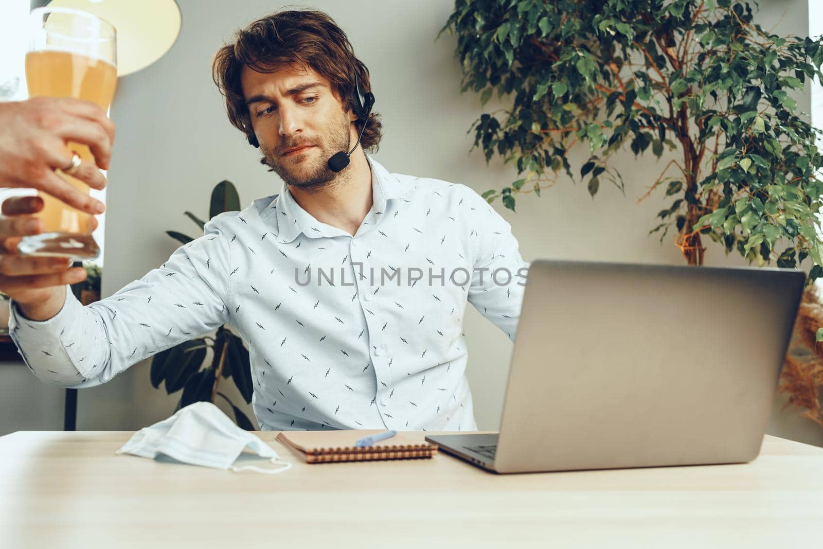 Bearded man using his laptop while drinking glass of beer sitting at his table