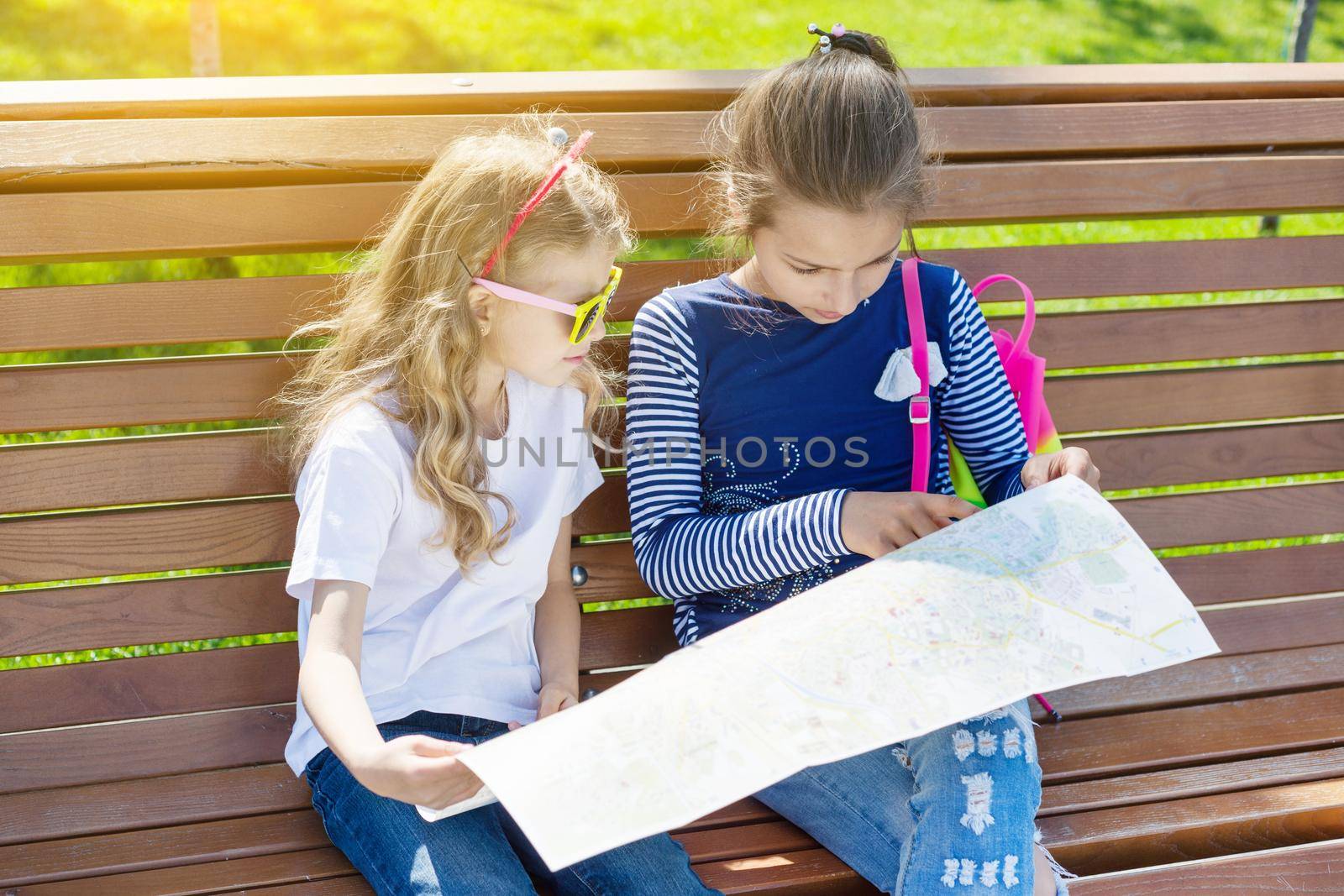 Outdoors portrait children tourists. With a map of city on the bench. by VH-studio