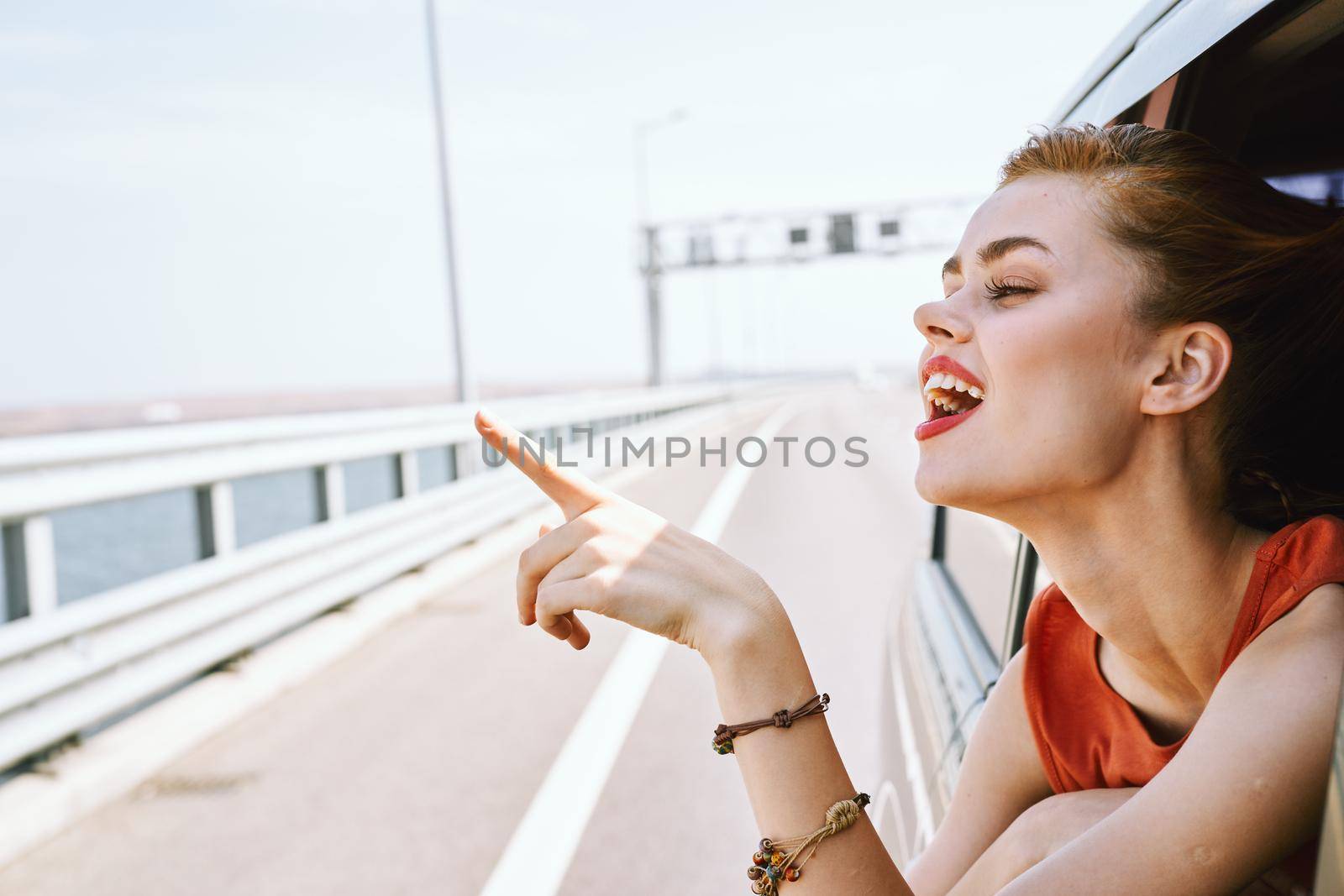 cheerful woman peeking out of the car window trip road travel. High quality photo
