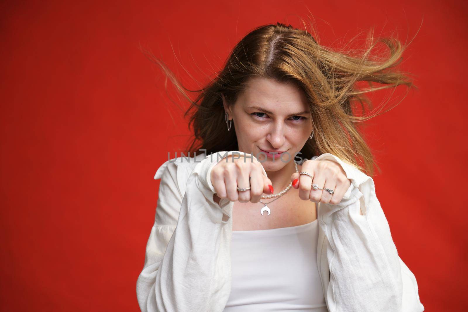 young girl shows comic boxing with fists in studio on red background