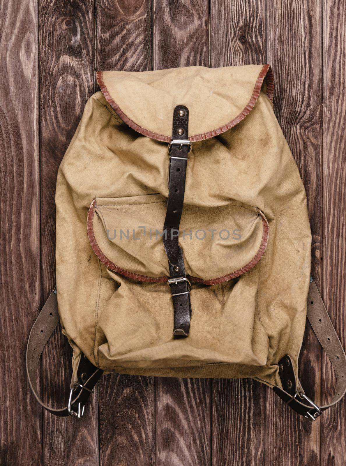 Old military backpack on wooden background, top view.