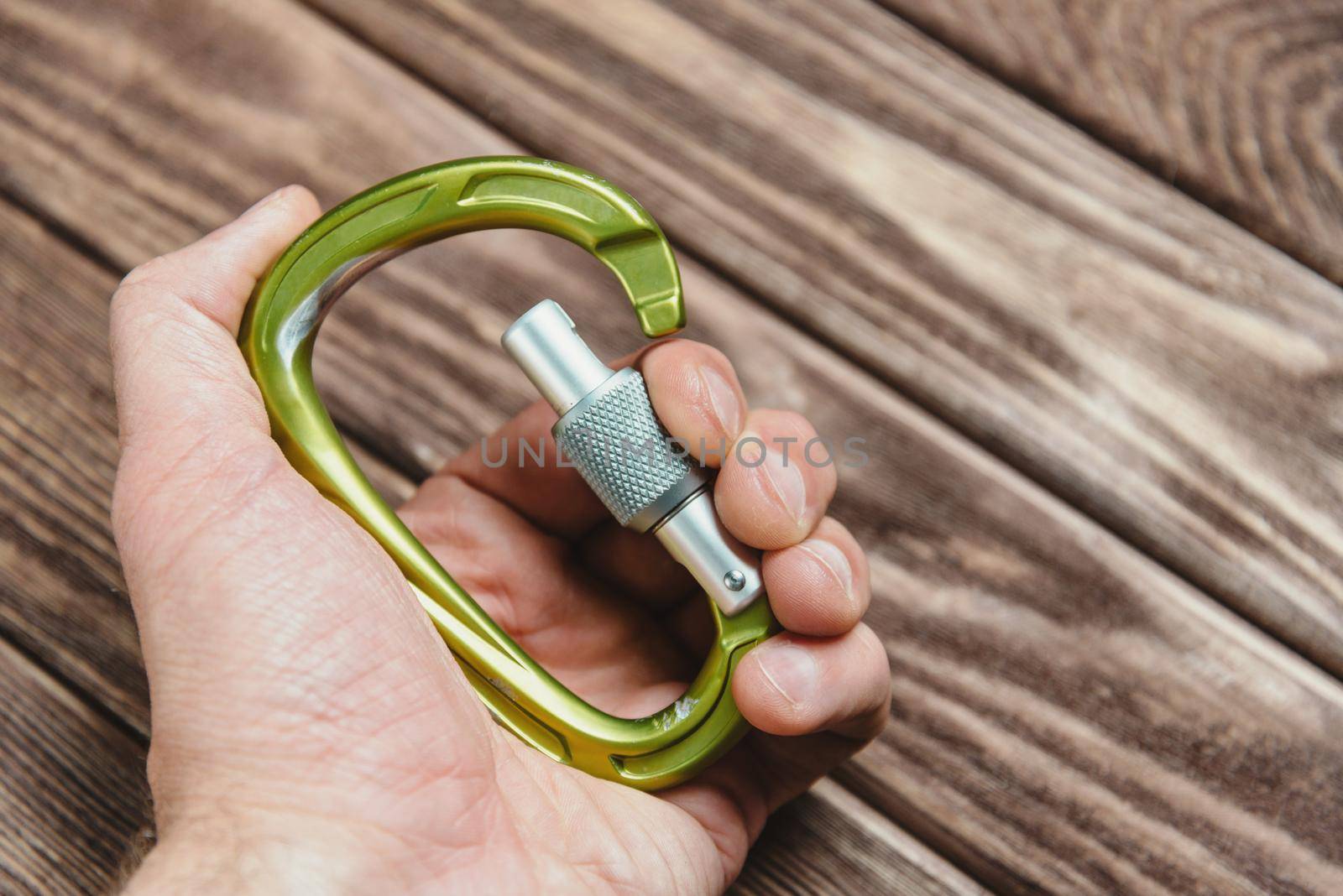 Male hand holds carbine on wooden background, close-up.