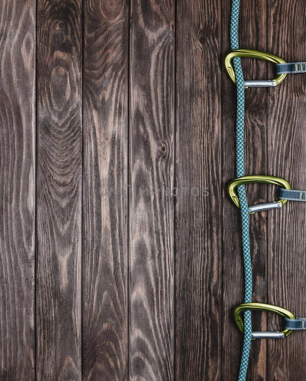 Climbing rope with quickdraws on a wooden background, top view. Copy-space.