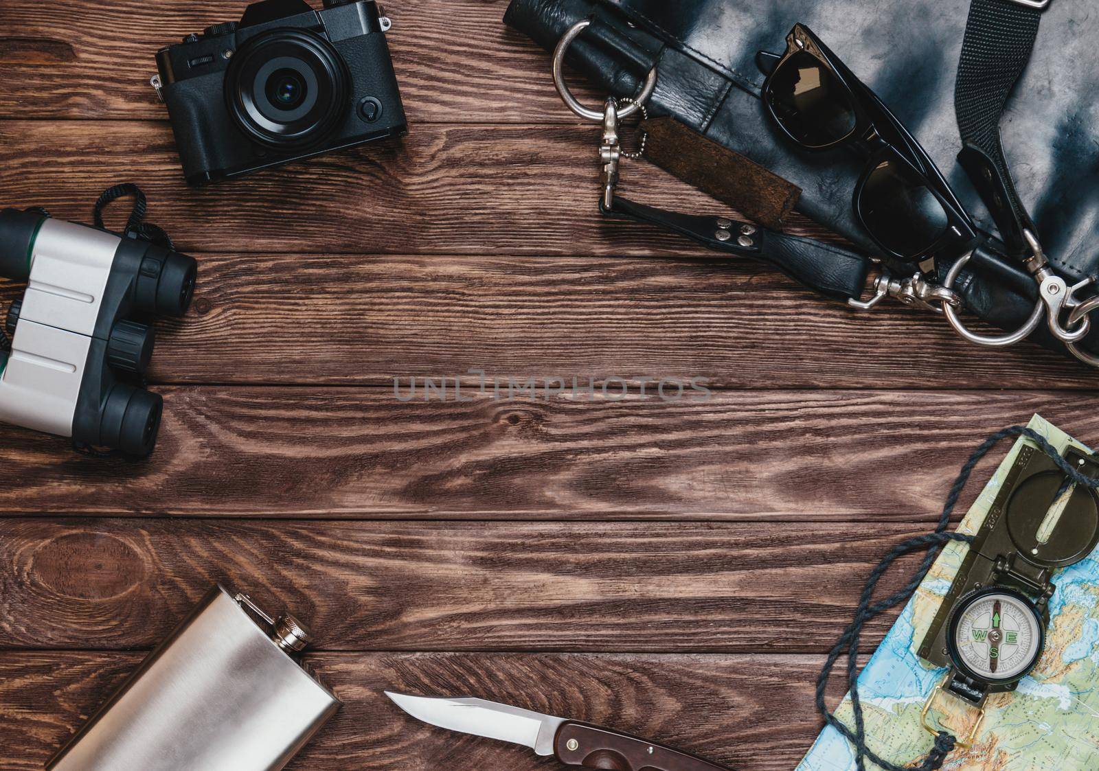 Equipment for journey and tourism on a wooden background, top view. Space for text in center of image.