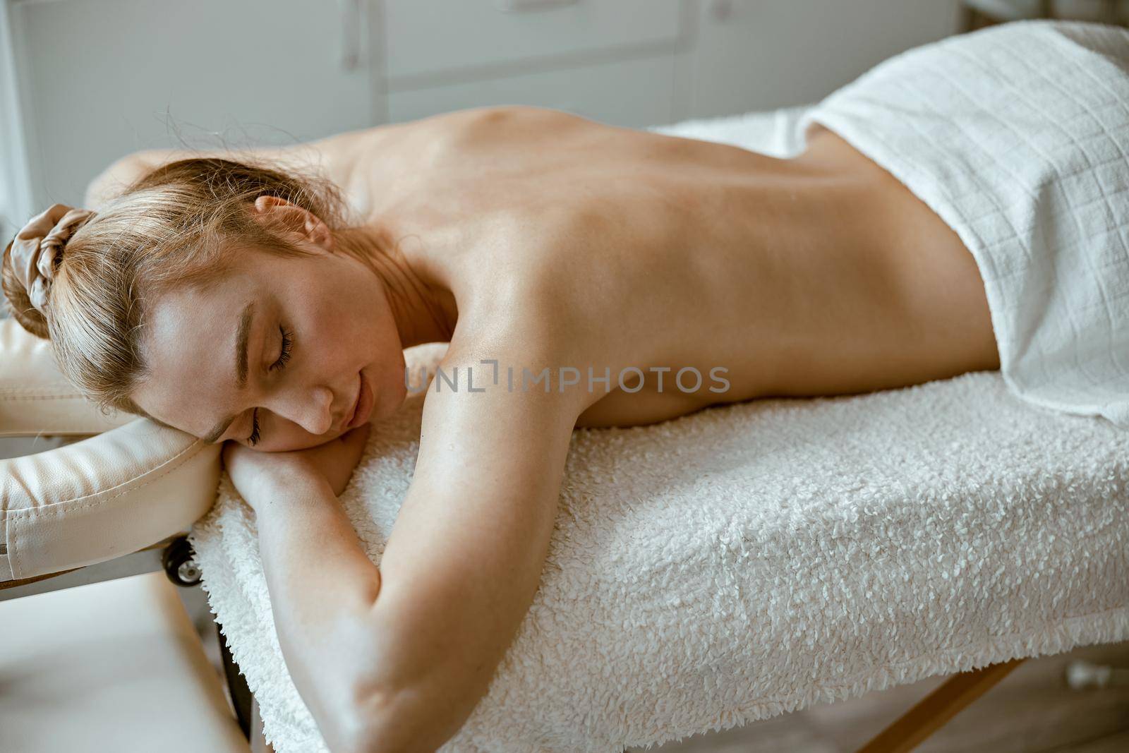 beautiful slim caucasian woman is relaxing on therapist table in spa salon