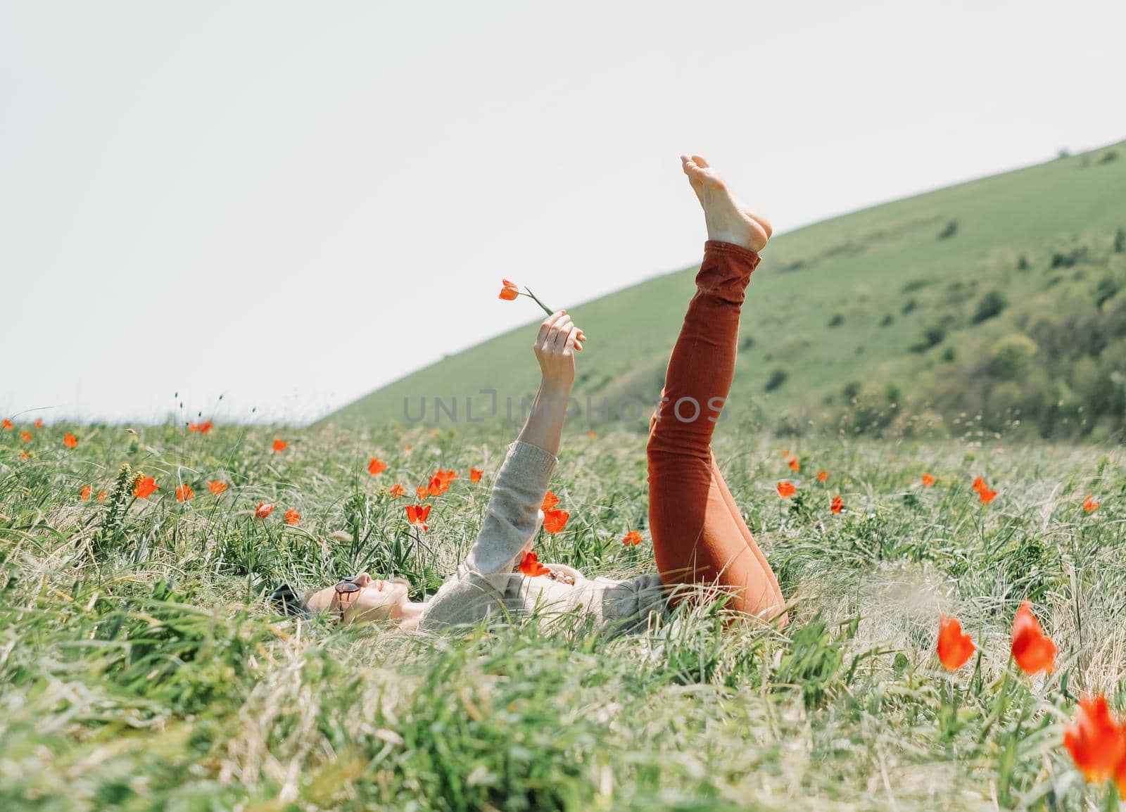 Young woman relaxing on red tulips meadow.