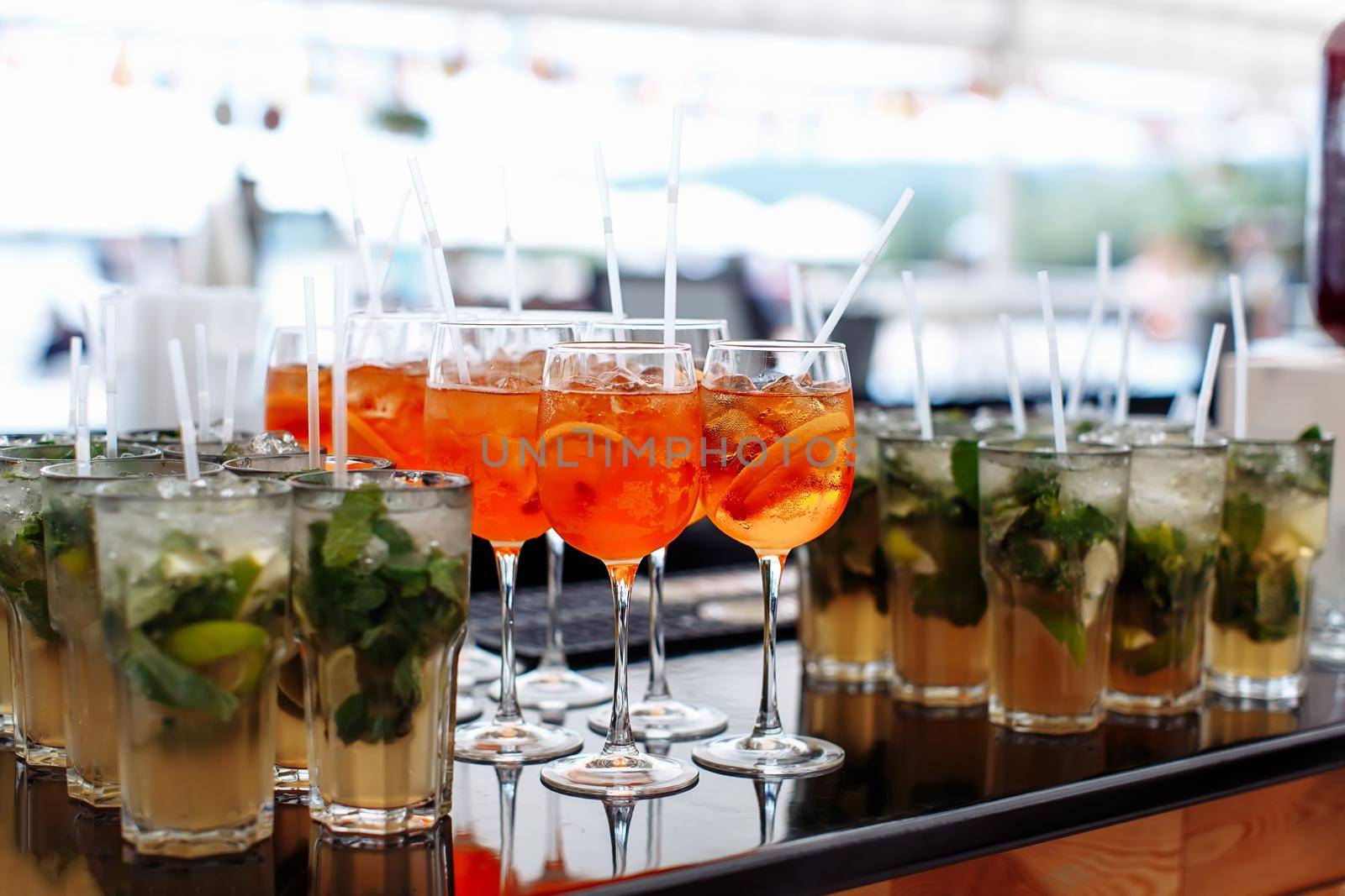 Lot of glasses with different cocktails with ice on the bar at the ceremony