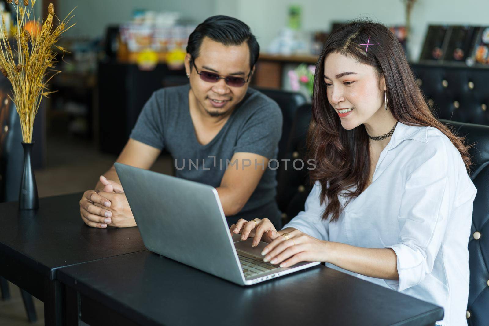 man and woman using laptop in a cafe