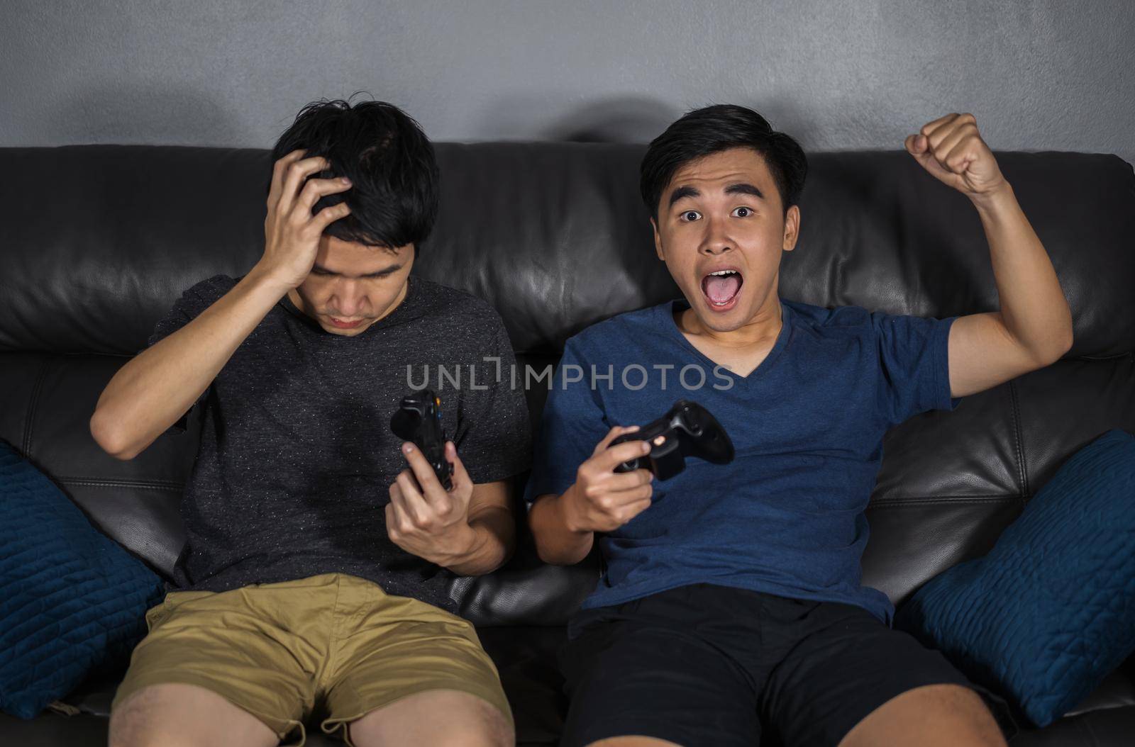 two man playing video games while sitting on sofa. win and lose emotions by geargodz