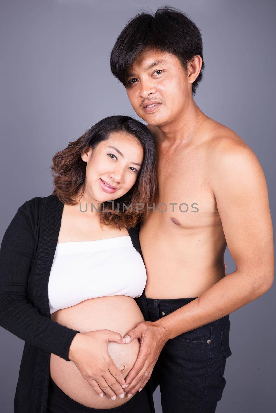 happy couple holding hands in heart shape on the belly