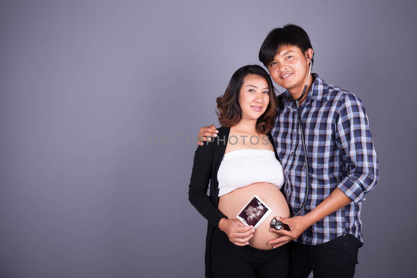 happy pregnant and husband with stethoscope and ultrasound image on gray background by geargodz