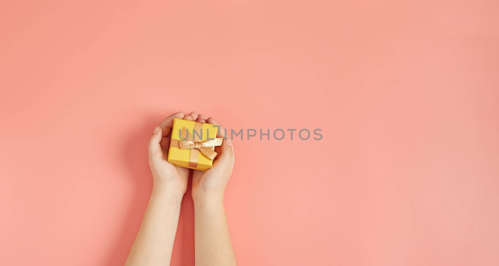 The child is holding a New Year's gift on a pink background with New Year's decorations.