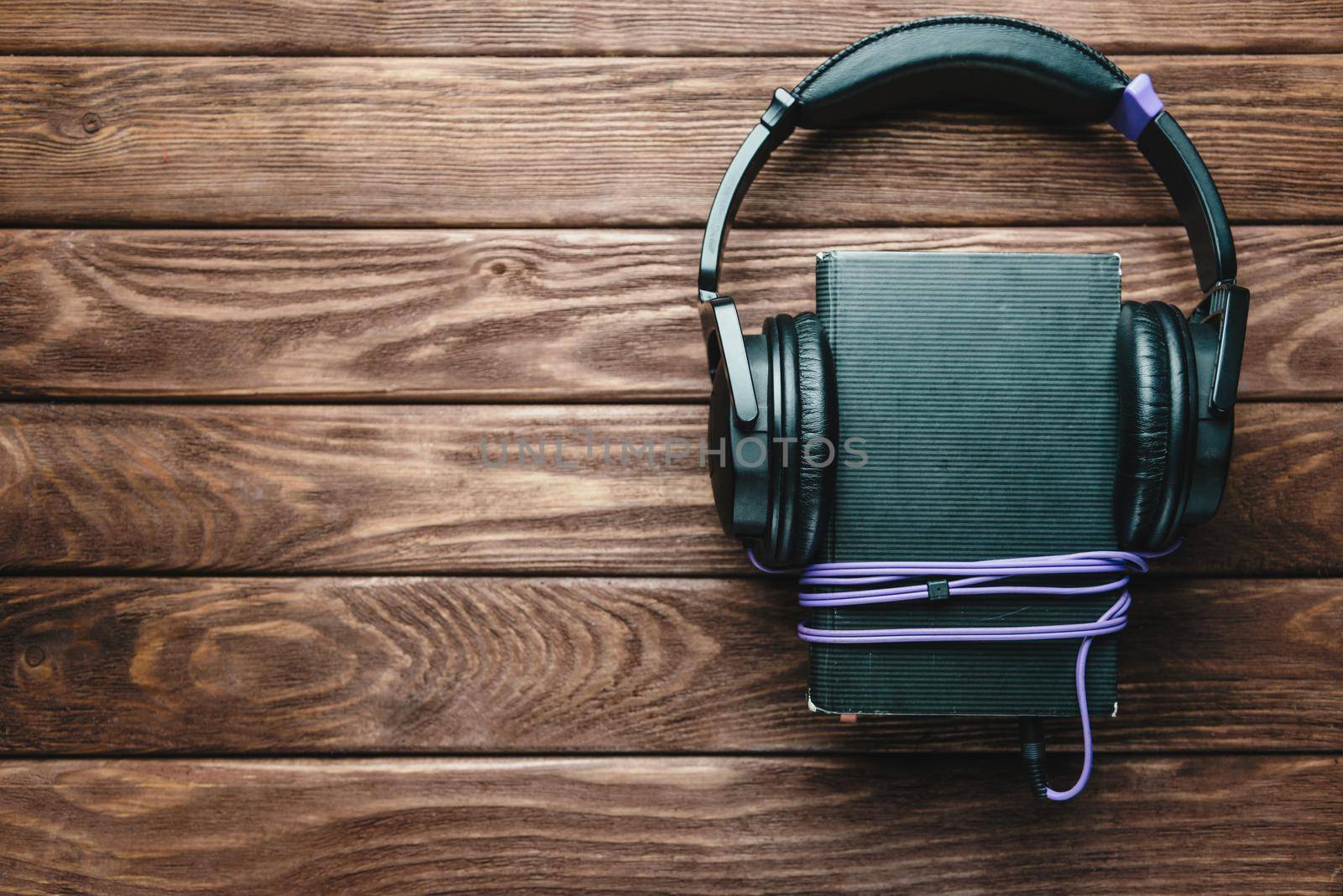 Headphones and book on a wooden background, top view, copy-space. Concept of audiobook.