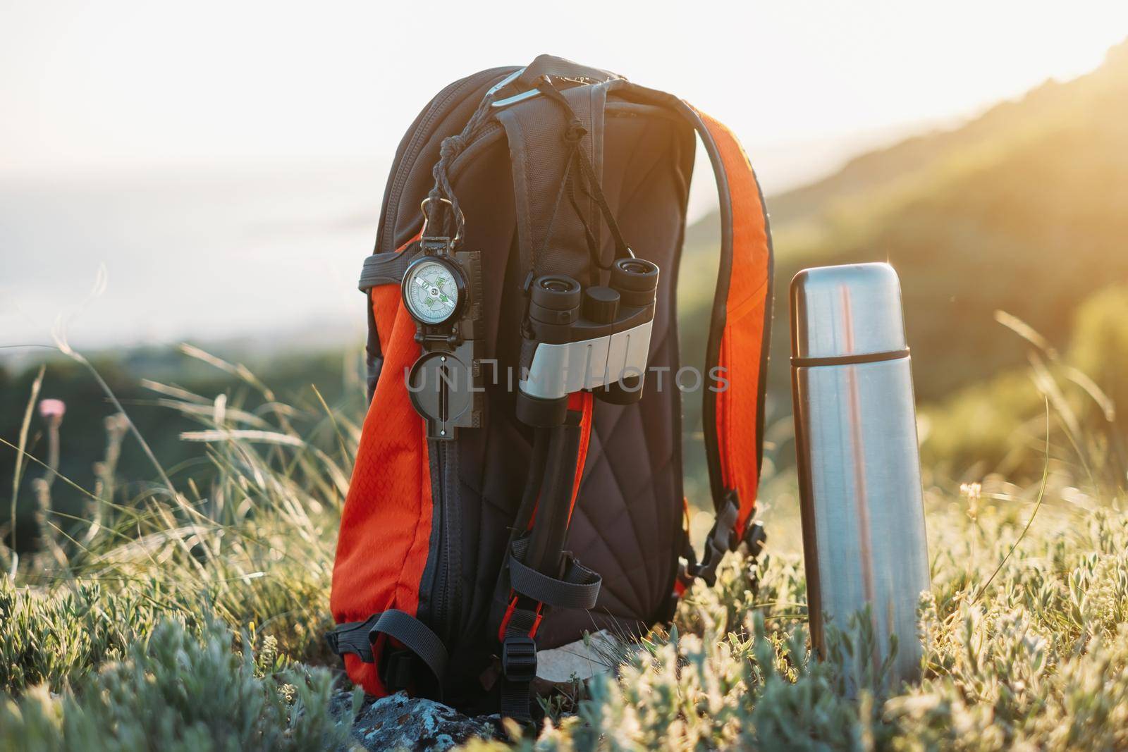 Hiking equipment outdoor: backpack, compass, binoculars and thermos.