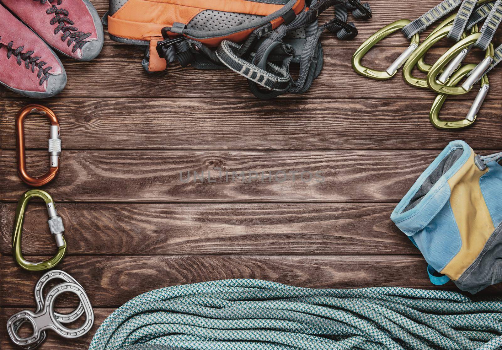 Climbing equipment on wooden background, top view. Space for text in center part of image.