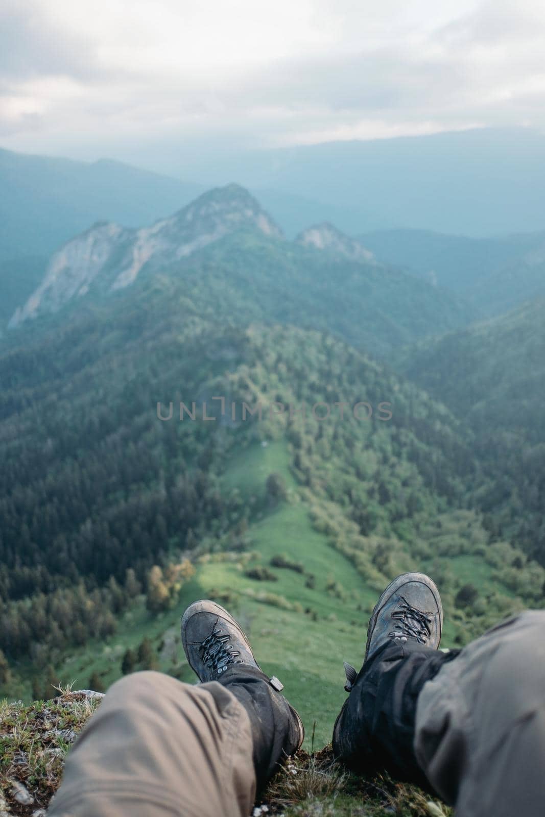 Traveler young man sitting in front of mountain ridge in summer, point of view.