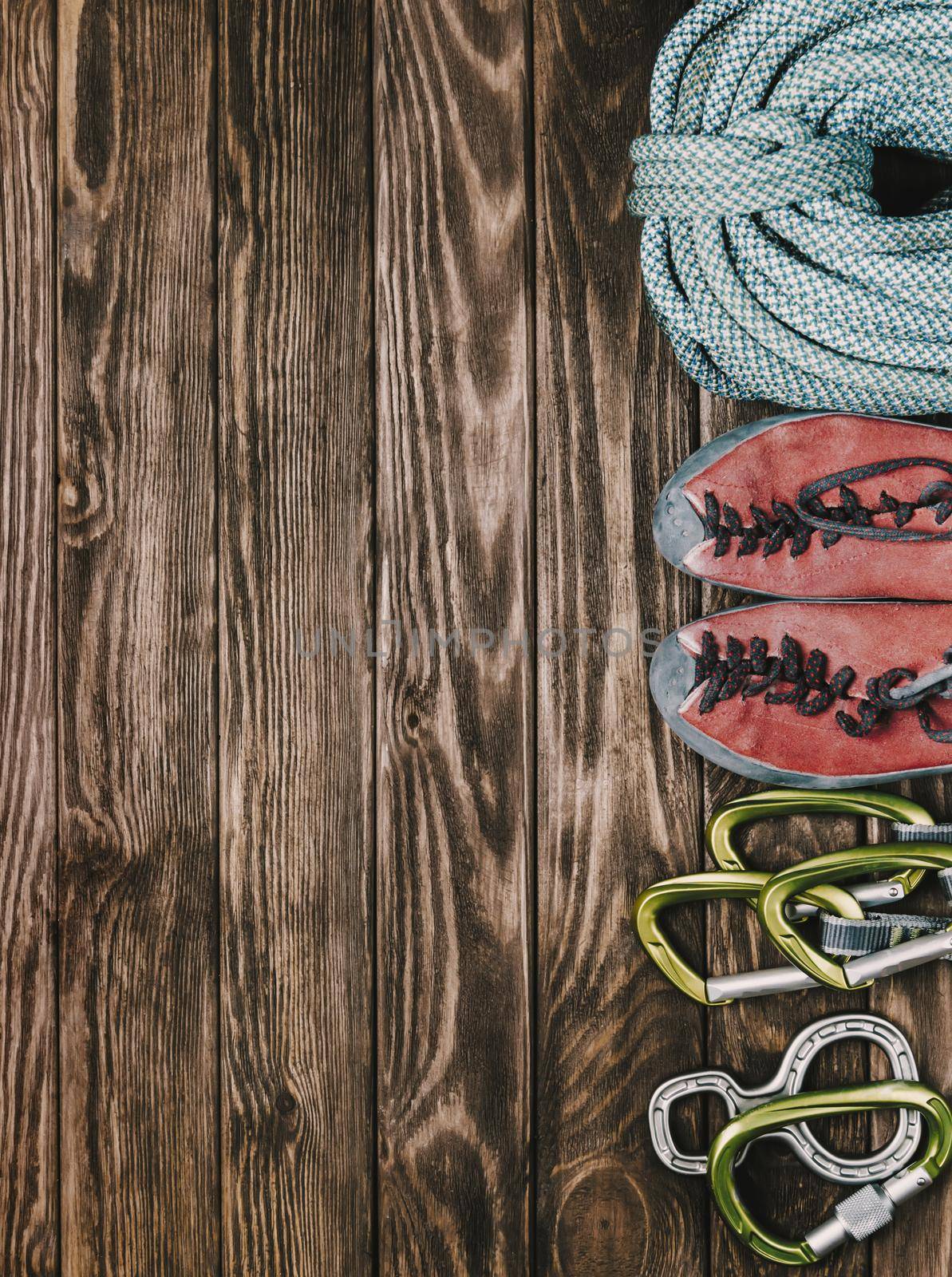 Equipment for rock climbing sport on wooden background, top view. Space for text in left part of image.