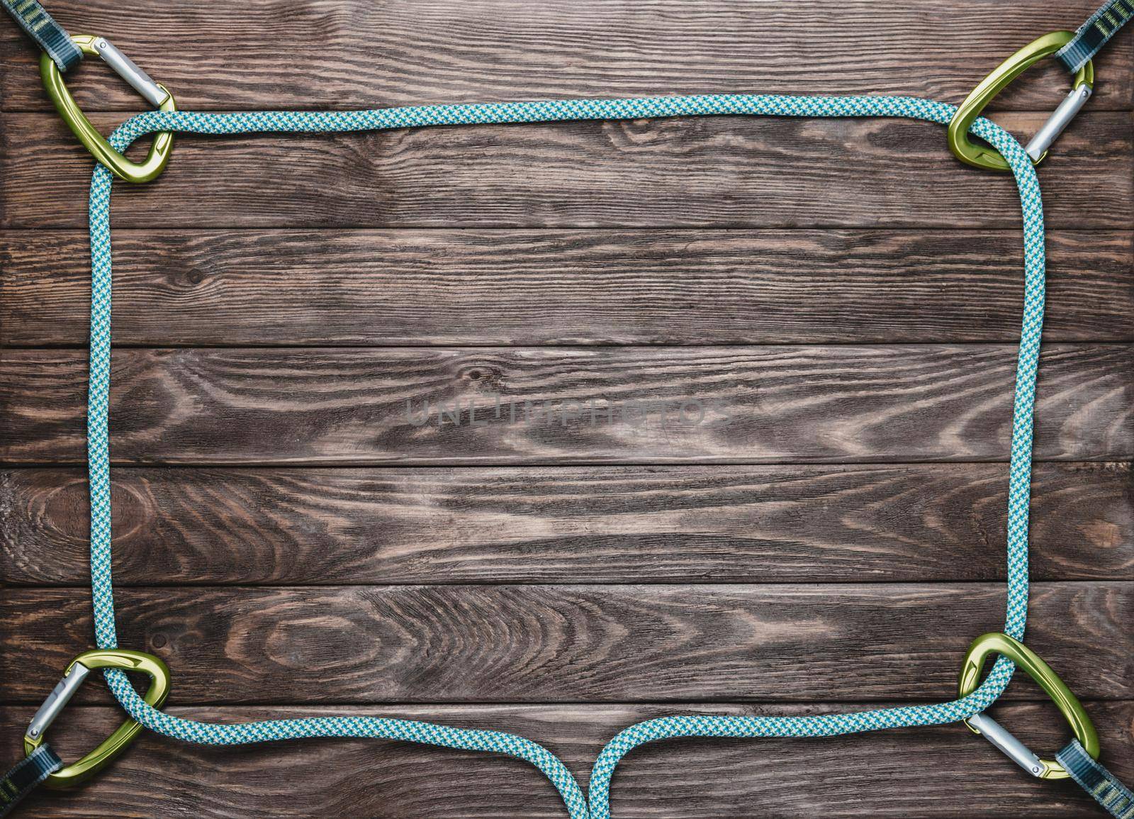 Climbing rope in the shape of a square with carbines on wooden background, top view. Space for text.