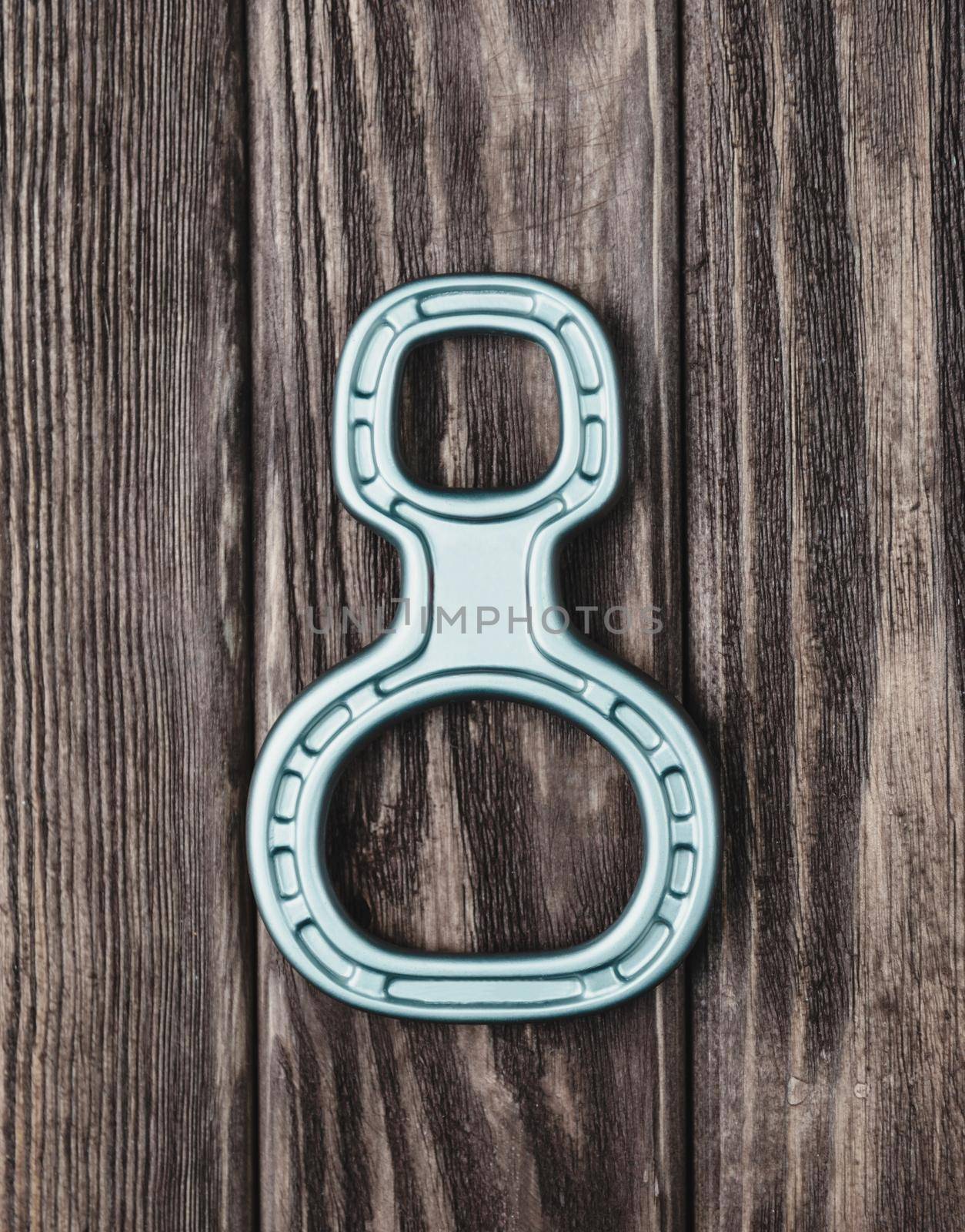 Climbing belay device figure eight on a wooden background, top view.