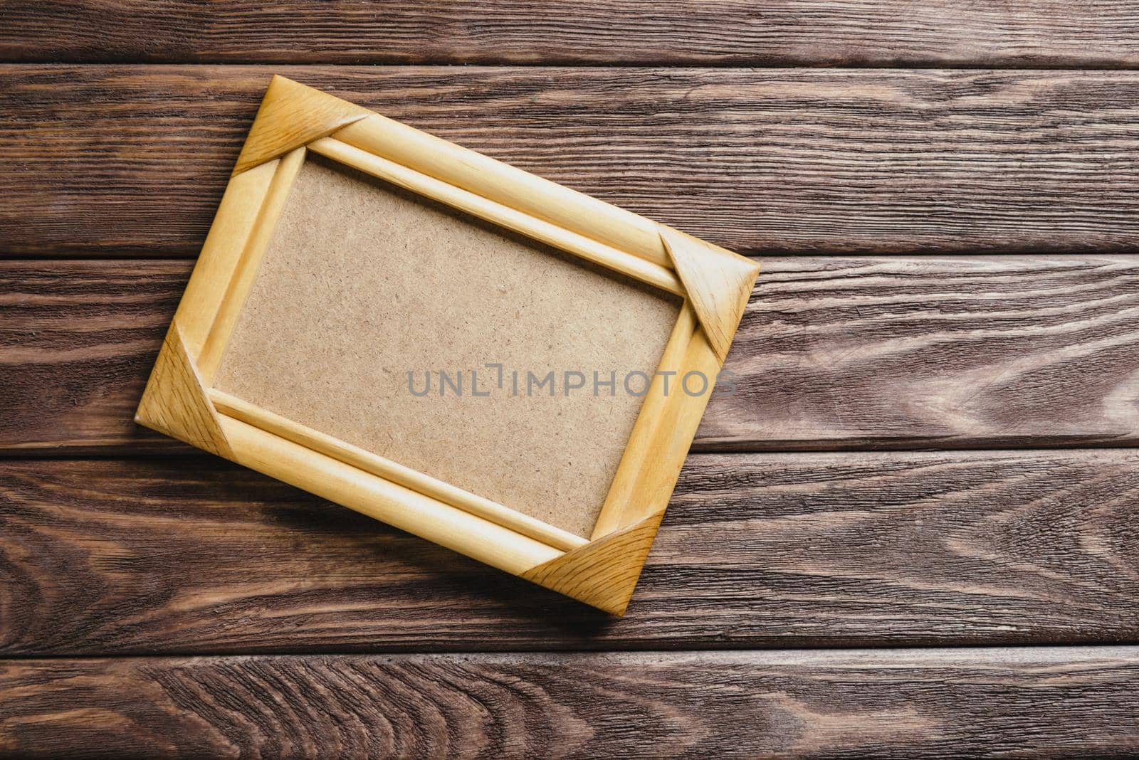 One empty frame on a dark wooden background, top view. Copy-space for text.