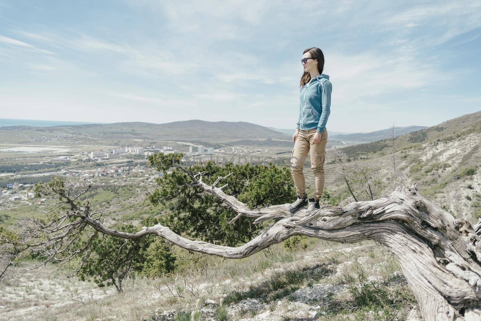 Explorer young woman standing on tree and looking into the distance.