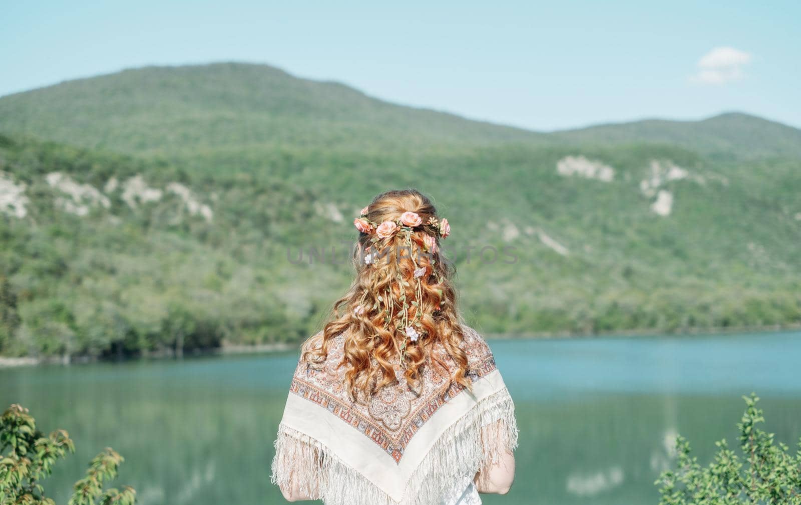 Beautiful woman with curly hairstyle enjoying view of nature in summer, rear view.