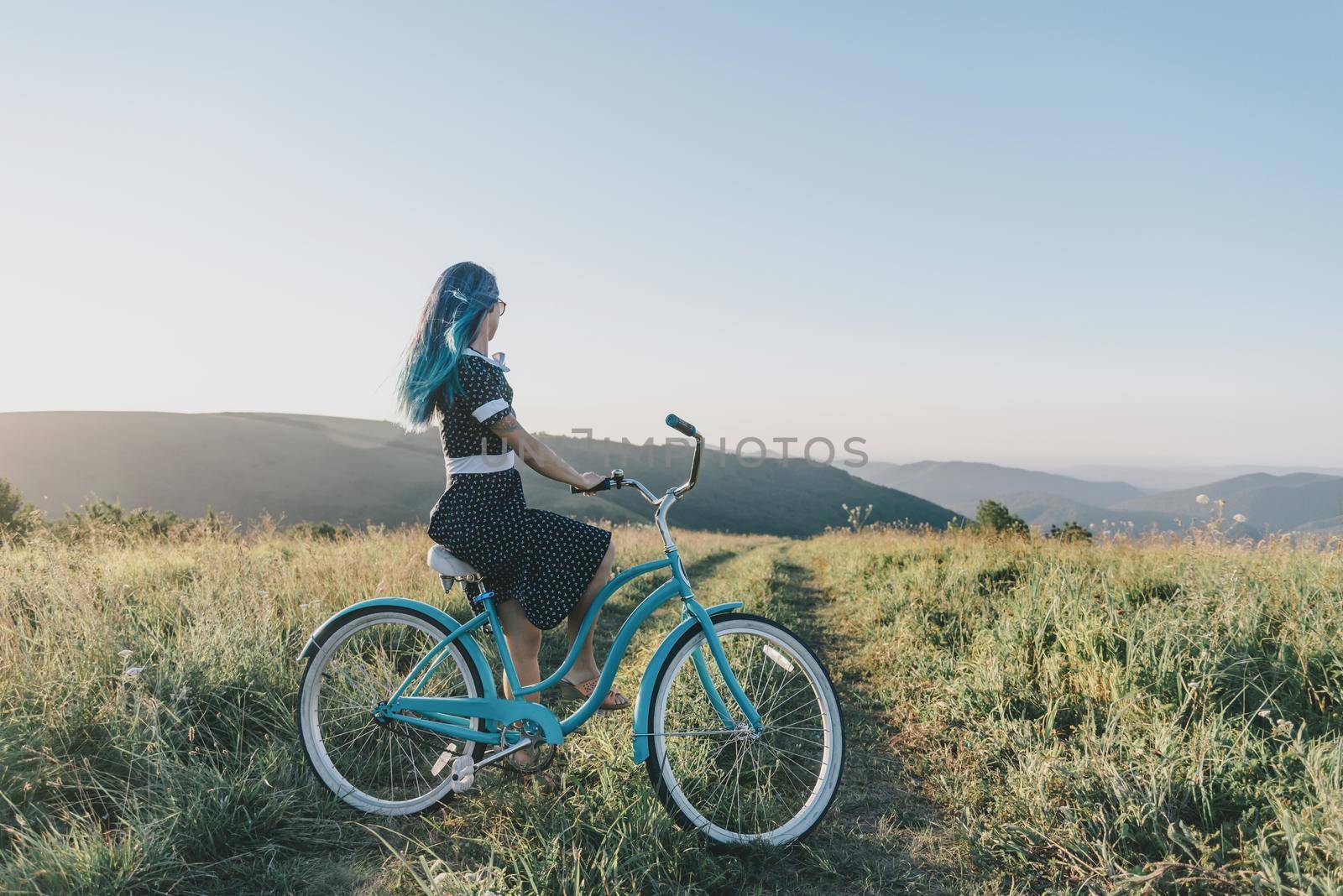 Girl sitting on cruiser bicycle and enjoying view of nature.