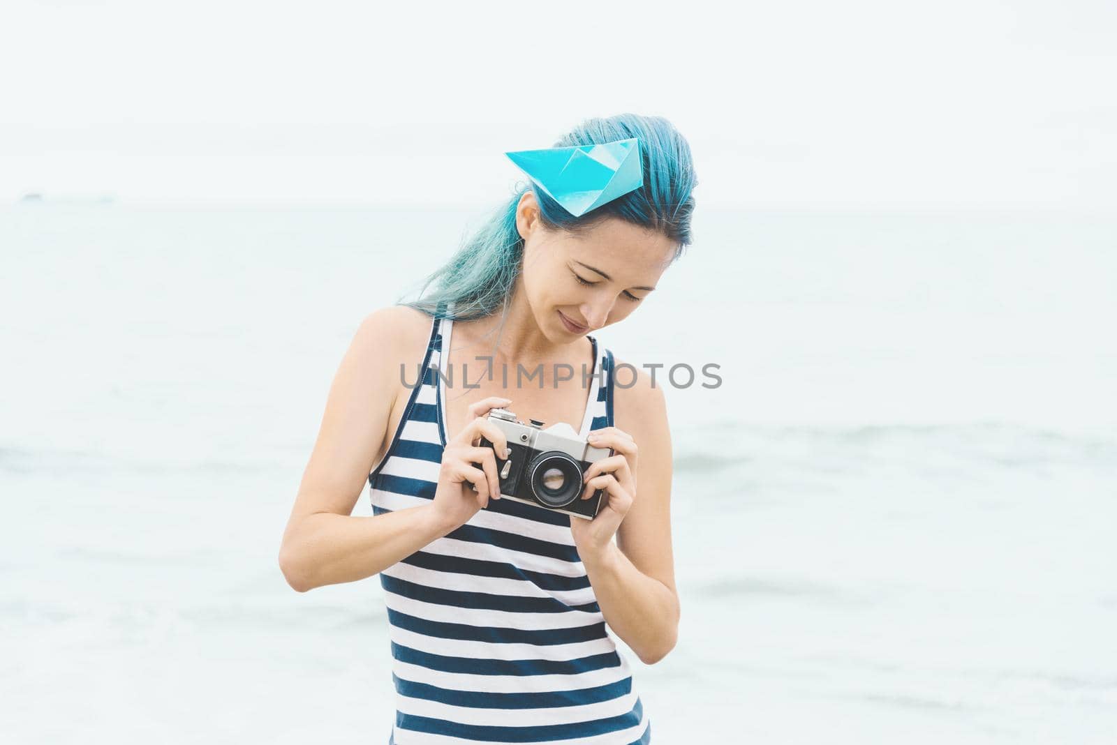Beautiful young woman with photo camera on background of sea.