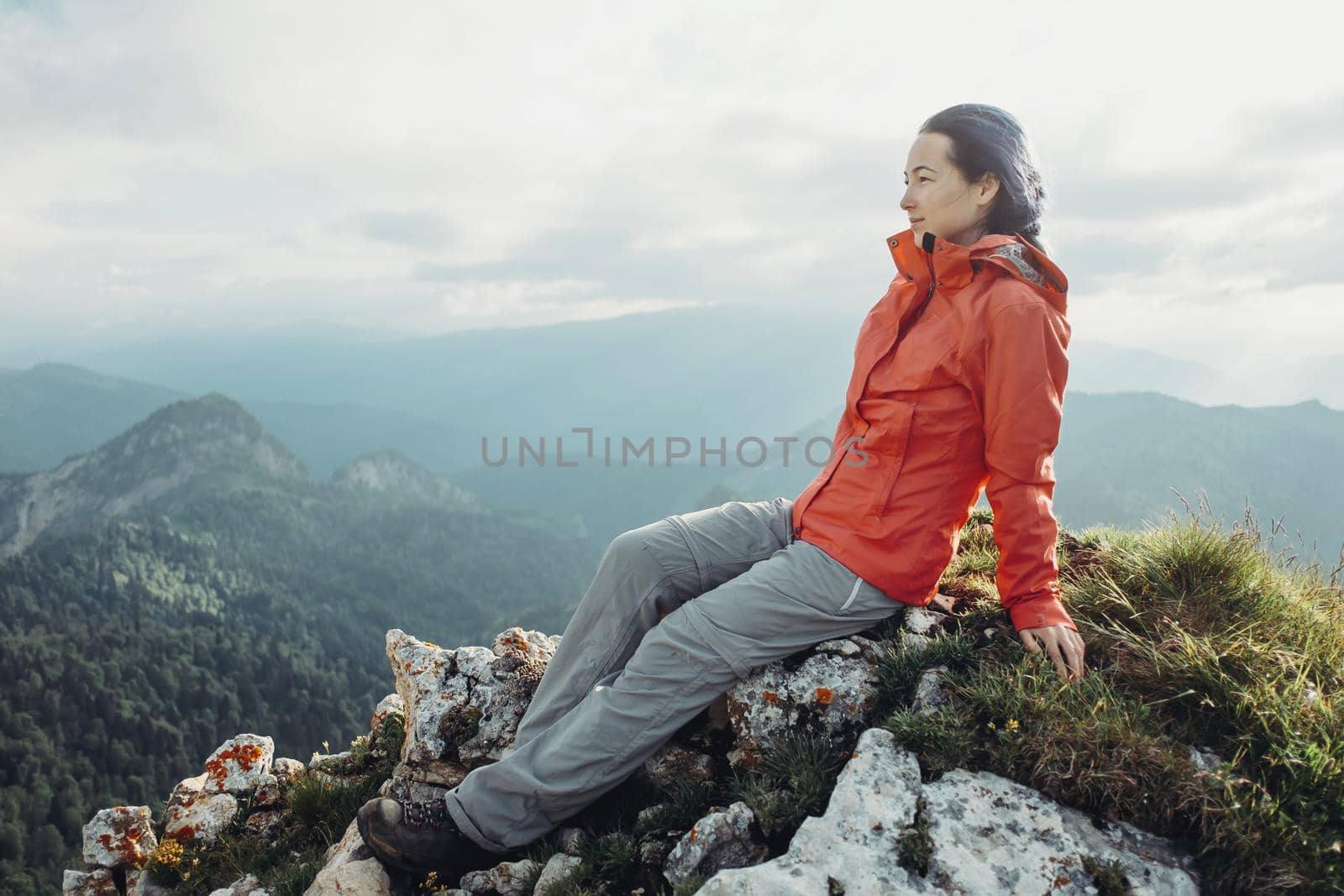 Hiker young woman resting on peak of mountain and enjoying view of nature in summer.