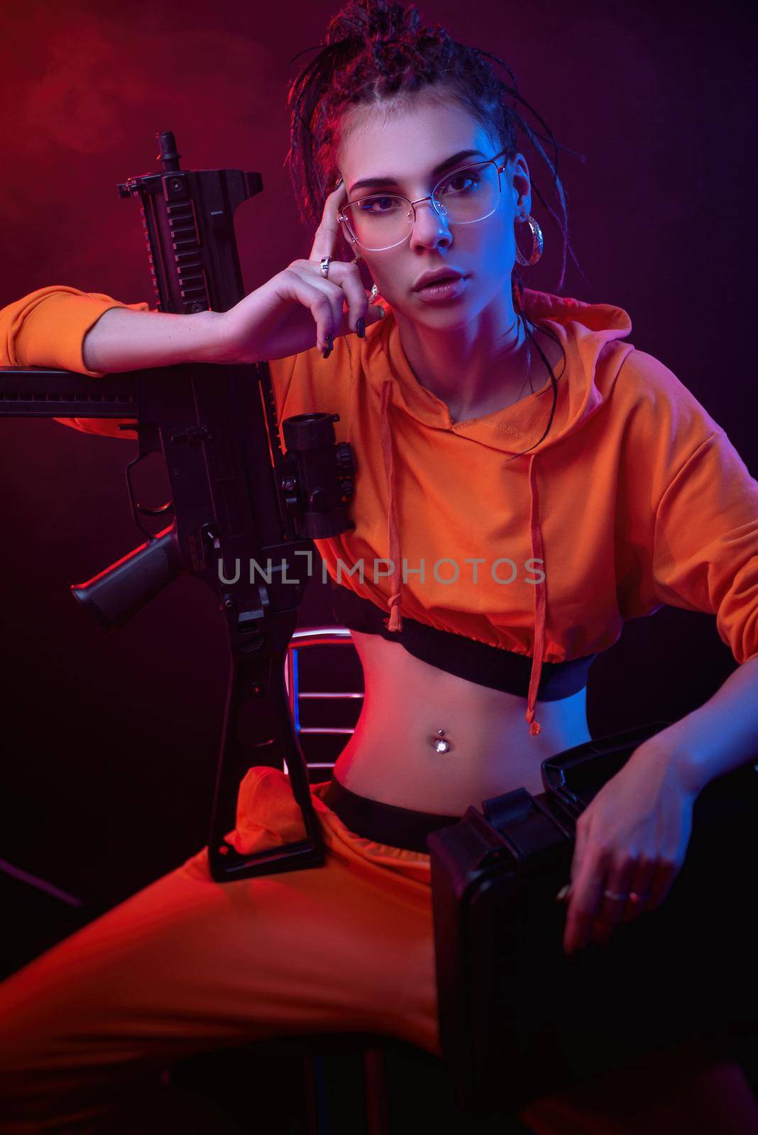 a bright brunette in a red jumpsuit with a short-barrelled automatic rifle on a dark background in neon light by Rotozey