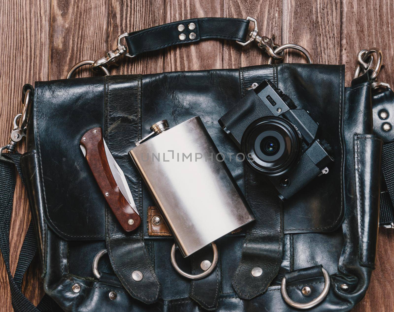 Bag with objects for travel on a wooden background, top view.