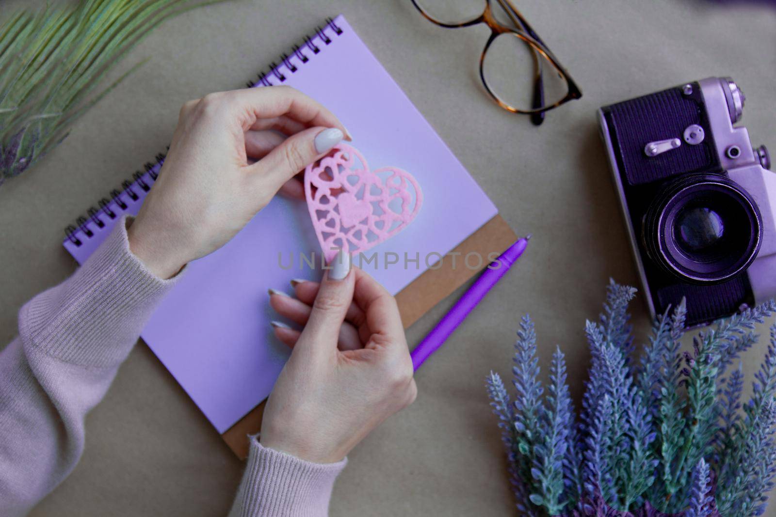 Wooden heart LOVE at woman hands behind notebook on the table and retro camera. Peace - harmony concept. holding Heart shape Love symbol. Valentines - romantic greeting lifestyle feelings concept