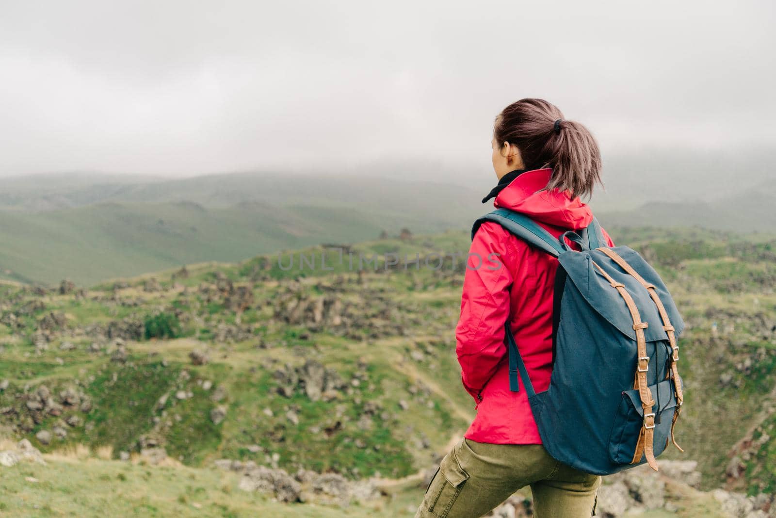 Explorer young woman with backpack walking in summer mountains.