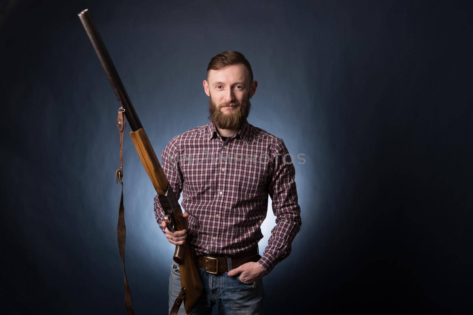 Man holding a shotgun on dark blue background.