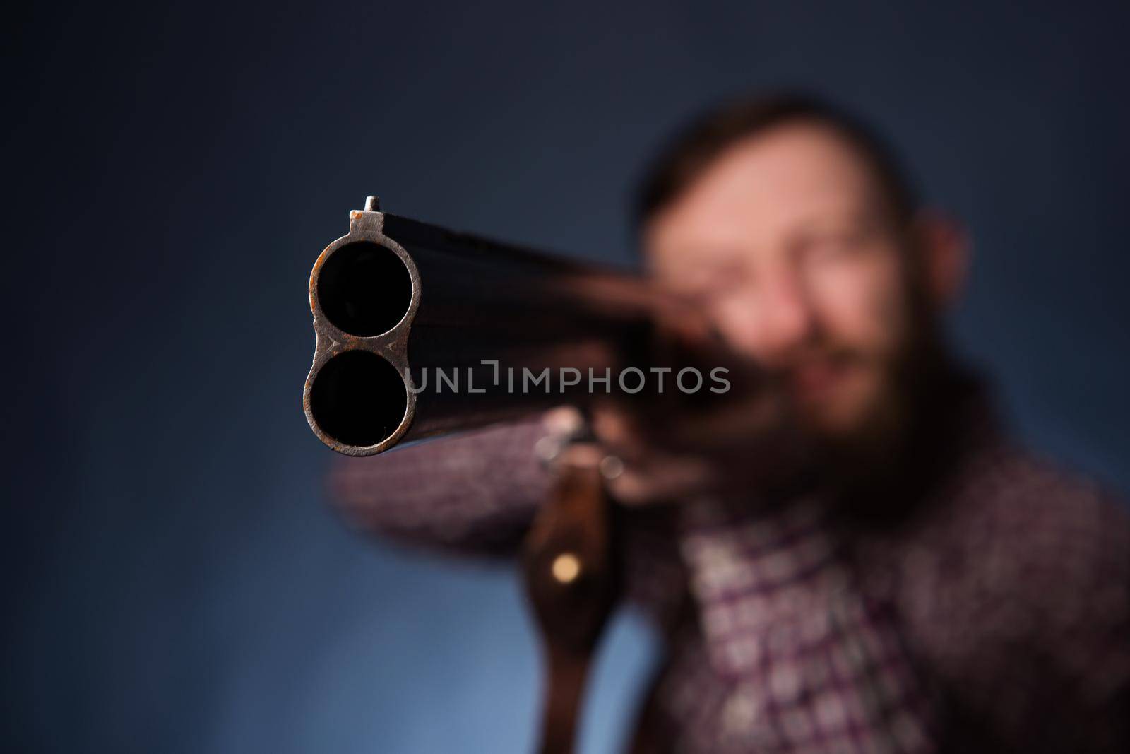 Man holding a shotgun on dark blue background.