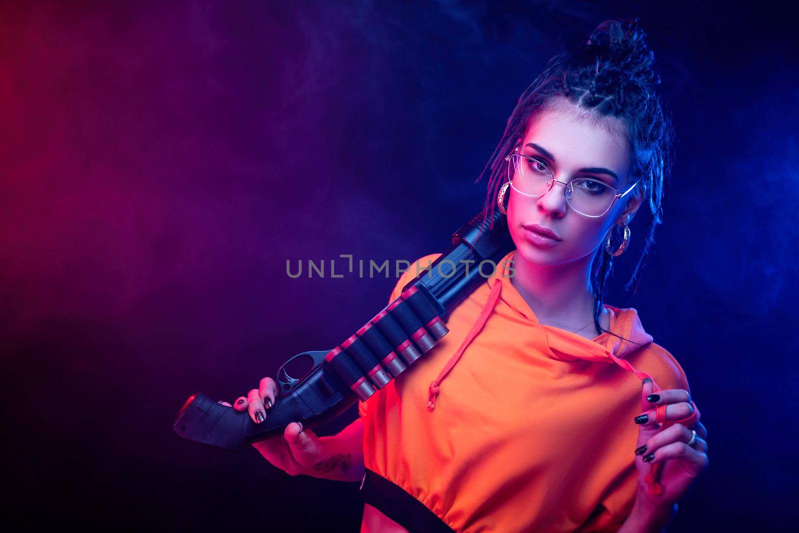 sexy brunette in an orange jumpsuit with a shotgun on a dark background in neon light by Rotozey