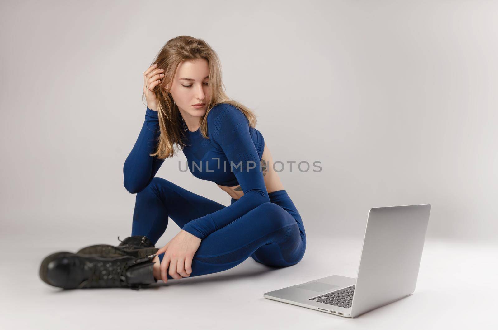 girl posing in the Studio performing exercises online on a laptop on a white background