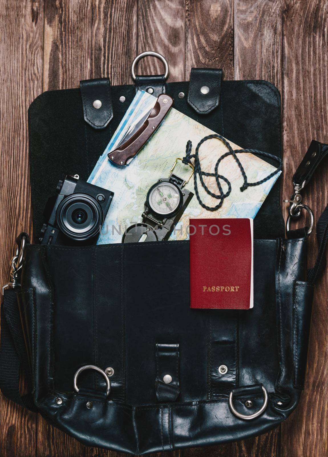 Travel objects in a suitcase on wooden background, top view.