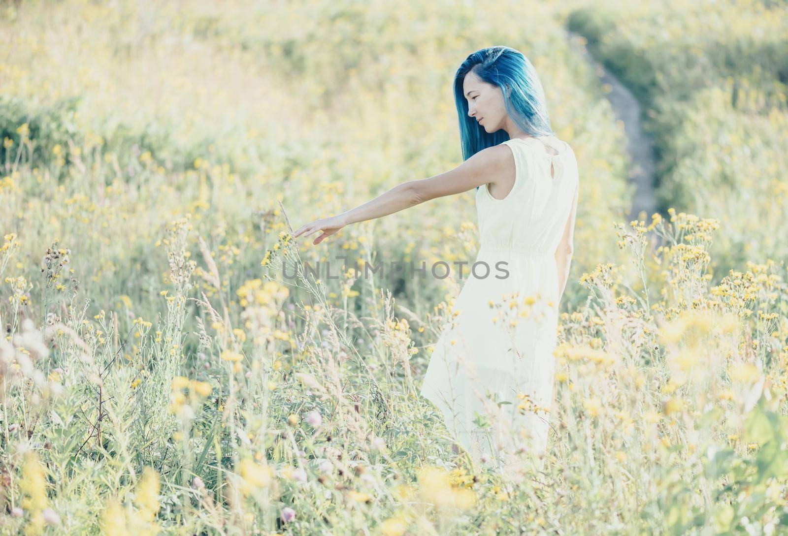 Beautiful young woman walking on wildflower meadow in summer.